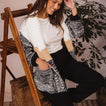 Woman wearing the oversized Hazy Sweater Cardigan with chunky yarns, colorblocking, and patch pockets sitting comfortably indoors
