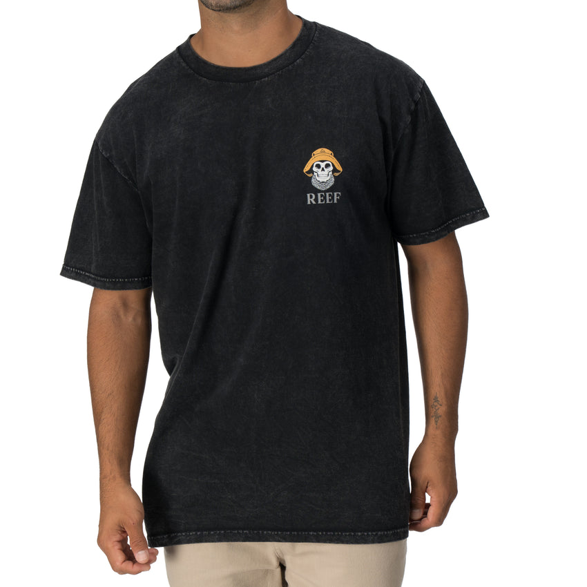 Man wearing a relaxed fit black Salty Short Sleeve Tee with vintage skull and bucket hat artwork on chest, beach apparel.