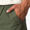 Close-up of a man's hand in the front pocket of the men's Matthew Twill Pant in olive green, showing texture and REEF tag.