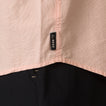 Close-up of the hem and REEF label on the Collins Ss Woven Shirt in soft peach, showcasing surf-inspired apparel detail.