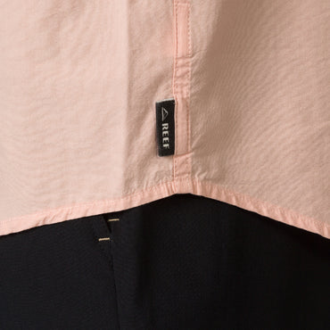 Close-up of the hem and REEF label on the Collins Ss Woven Shirt in soft peach, showcasing surf-inspired apparel detail.