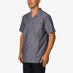 Man wearing a blue Harold Camp Shirt facing left, showing front and side with short sleeves and button closure.