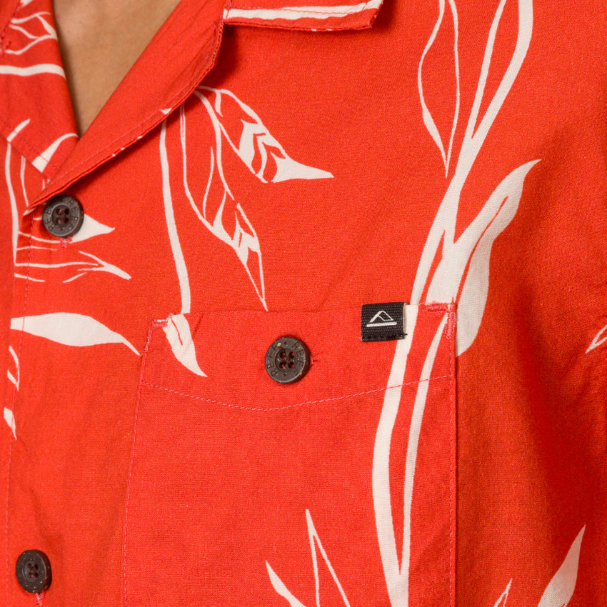 Close-up of the chest pocket and collar of the red Kaden Camp Shirt with white leaf print, showing button details.