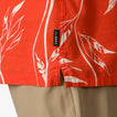 Close-up of the hem and side seam of the Kaden Camp Shirt in orange with white leaf prints, showing REEF tag.
