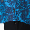 Close-up of the hem and label on the blue Tyson Classic Shirt with dark tropical leaf print for men.