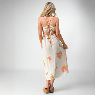 Woman wearing Belladona Dress with floral print and open back, paired with tan platform sandals facing away in studio.