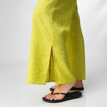 Close-up of the lower legs wearing Ollie Pant in bright yellow with print, facing right, paired with black sandals.