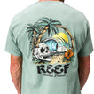Akin Tee on a man, back view, featuring a beach graphic with palm trees, waves, a skull, and reef branding.