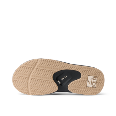 Fanning men's flip flop outsole facing up, brown herringbone tread with black bottle opener and REEF logo for beach comfort