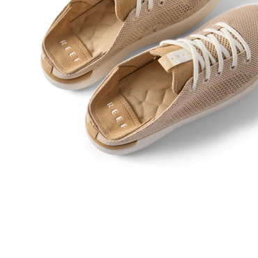 Reef Neptune women's shoes facing left with close-up on cushioned insoles and breathable knit upper in metallic gold.