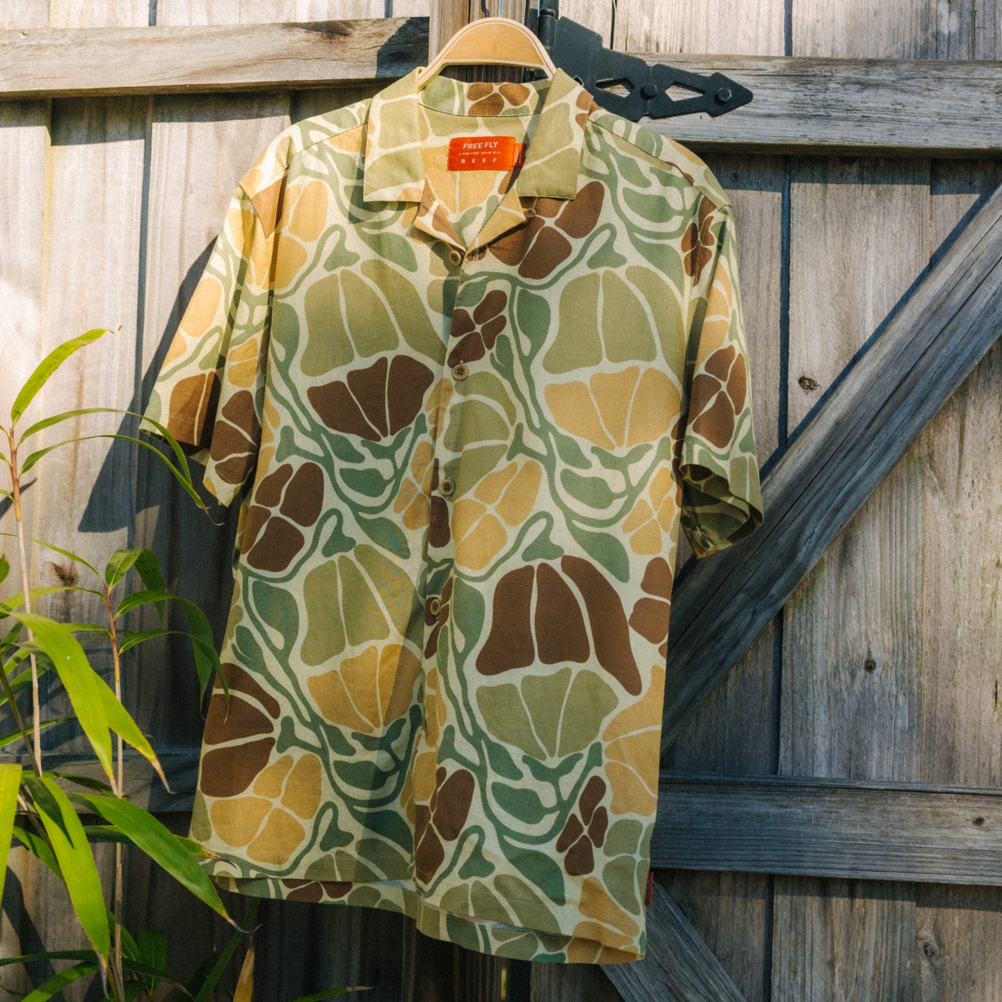 Men's Sullivan's Camp Shirt - Floral Camo hanging on wooden gate, lightweight with relaxed fit and surf-inspired style