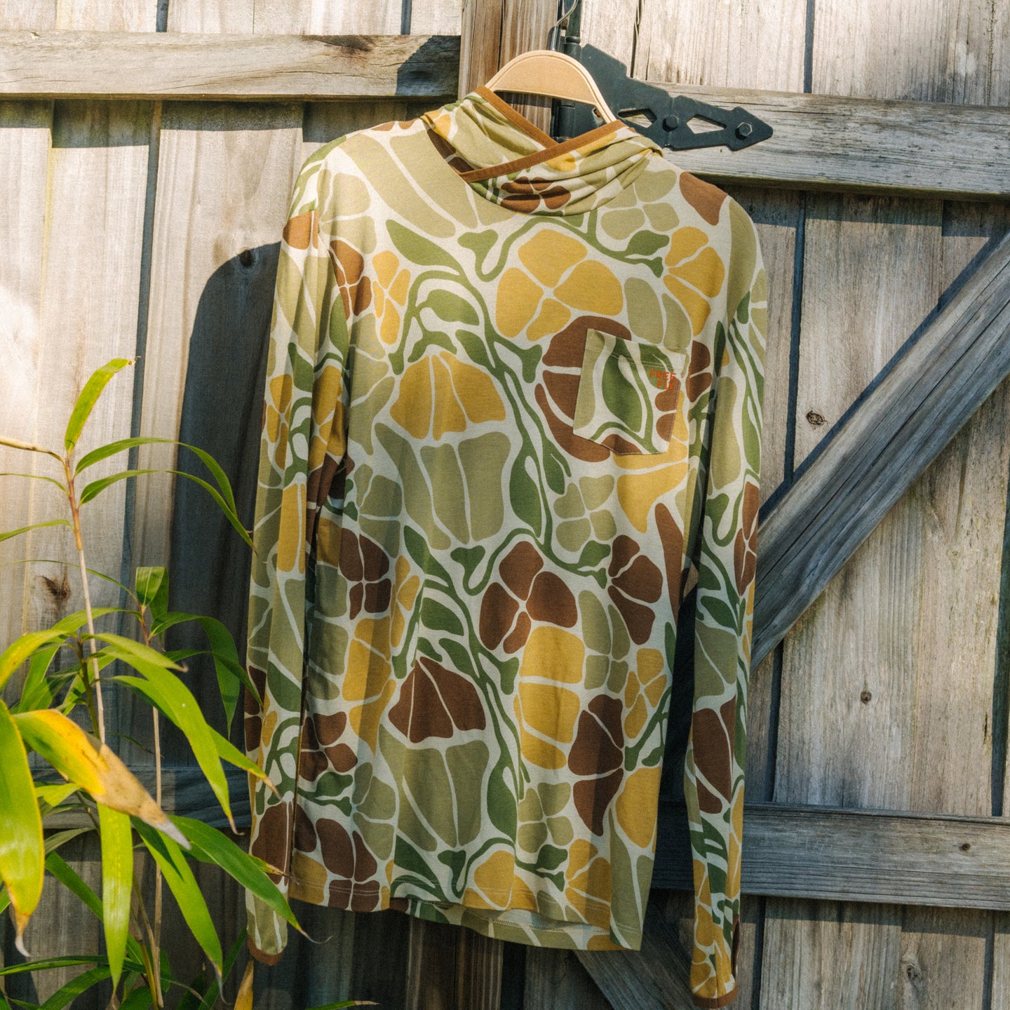 Men's Bamboo Lightweight Hoodie - Floral Camo hanging on wooden fence, lightweight breathable fabric, surf-inspired comfort design
