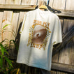Back view of High-Stoke Relaxed Tee - Bone hanging outdoors showing surf-inspired graphic with beach lifestyle vibe