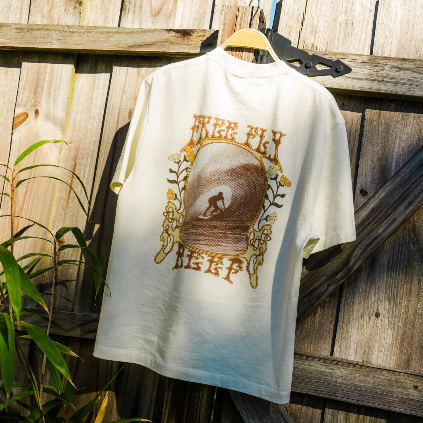 Back view of High-Stoke Relaxed Tee - Bone hanging outdoors showing surf-inspired graphic with beach lifestyle vibe