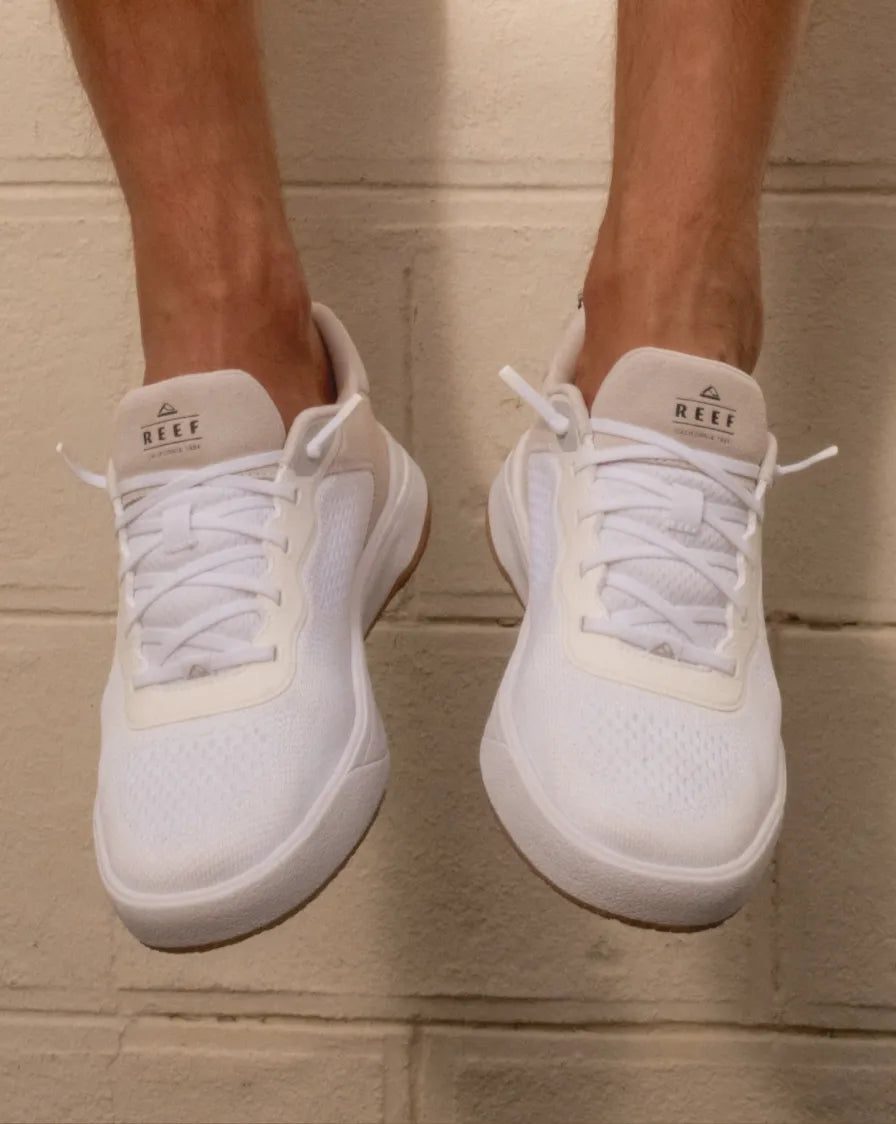 Pair of right-facing white REEF sneakers with mesh upper and laces, shown from front on neutral background