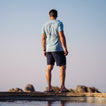 Man wearing La Loca Tee facing away, standing on beach pier with surf-inspired comfort and water-friendly design.