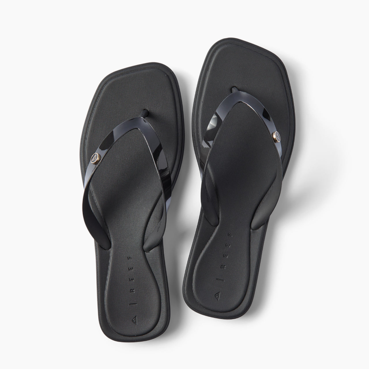 Solaye black square toe flip flops with glossy jelly straps toes facing upward
