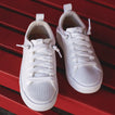 Top-front view of white Lay Day Lite women's sneakers with lightweight breathable mesh and cushioned arch support on red bench.