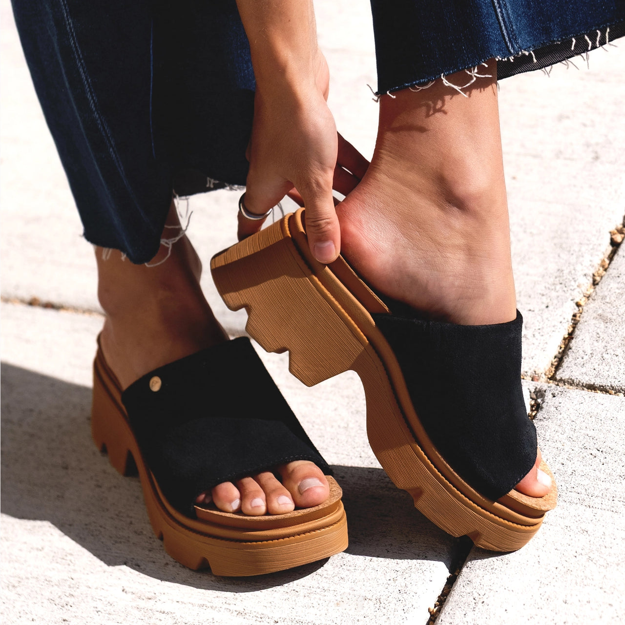 Vista Luxe Evie showing right foot sliding into black suede mule facing left with thick platform sole, soft cushioning design.