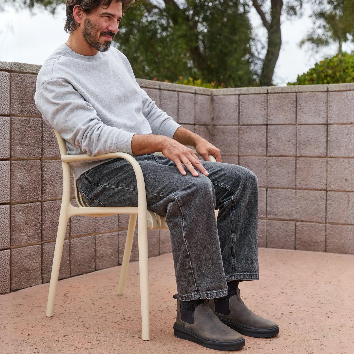 Man sitting outdoors wearing Evo black leather mid-cut boots facing right, showcasing comfort and casual style.