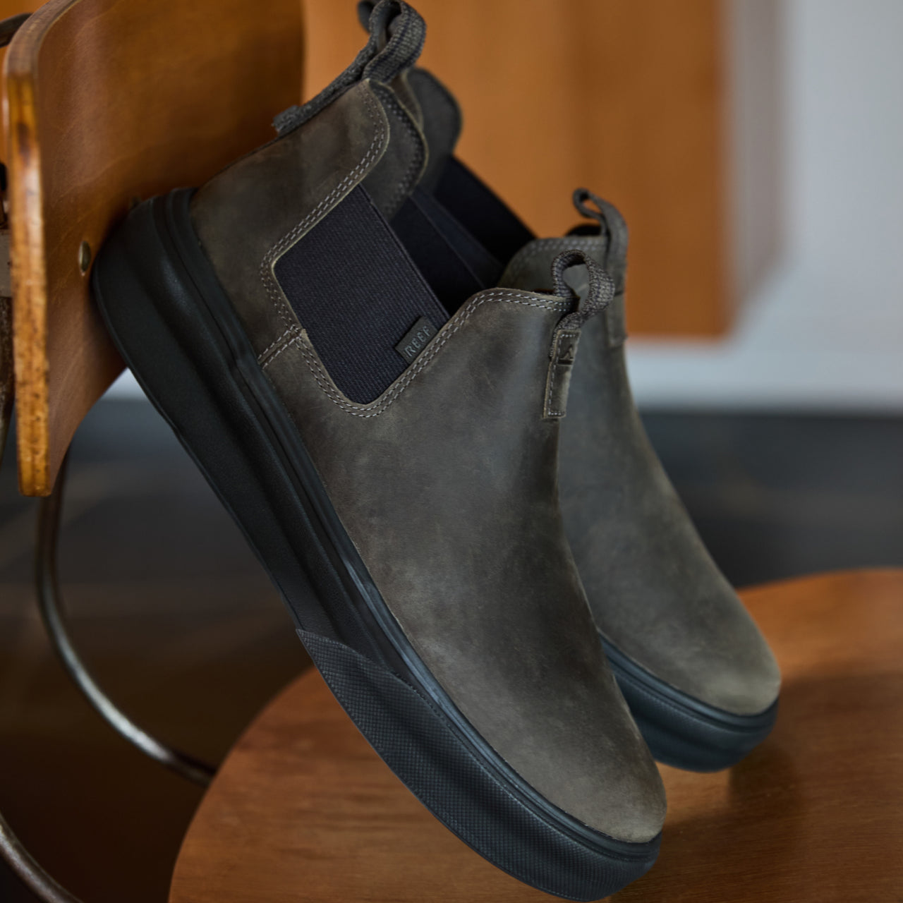 Pair of right-facing Evo men's leather boots with extra cushion and arch support on a wooden chair seat