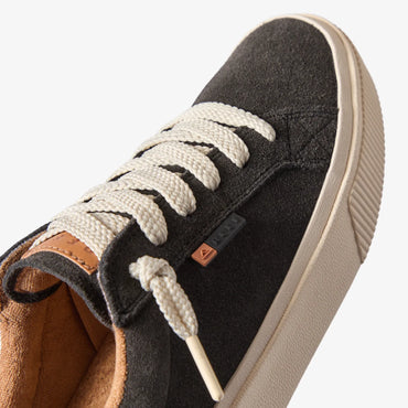 Close-up of the front and side of the Lay Day Dawn charcoal suede sneaker facing right, showing laces and arch support.