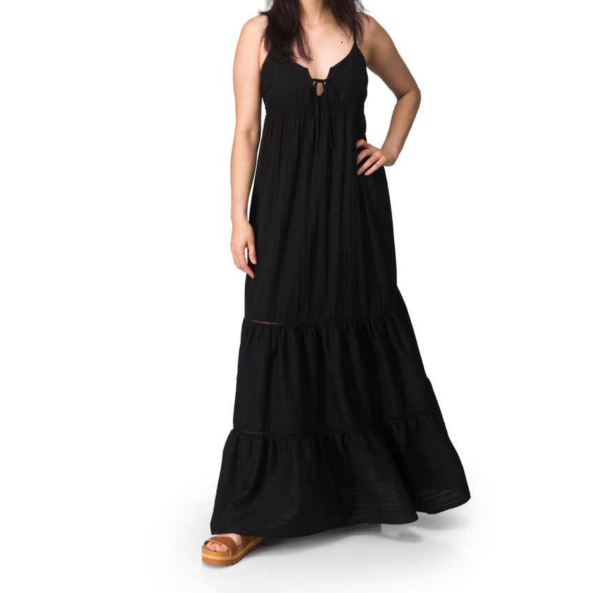 Woman wearing Yuni Maxi Dress with deep neckline and tie detail, paired with tan REEF sandals facing forward.