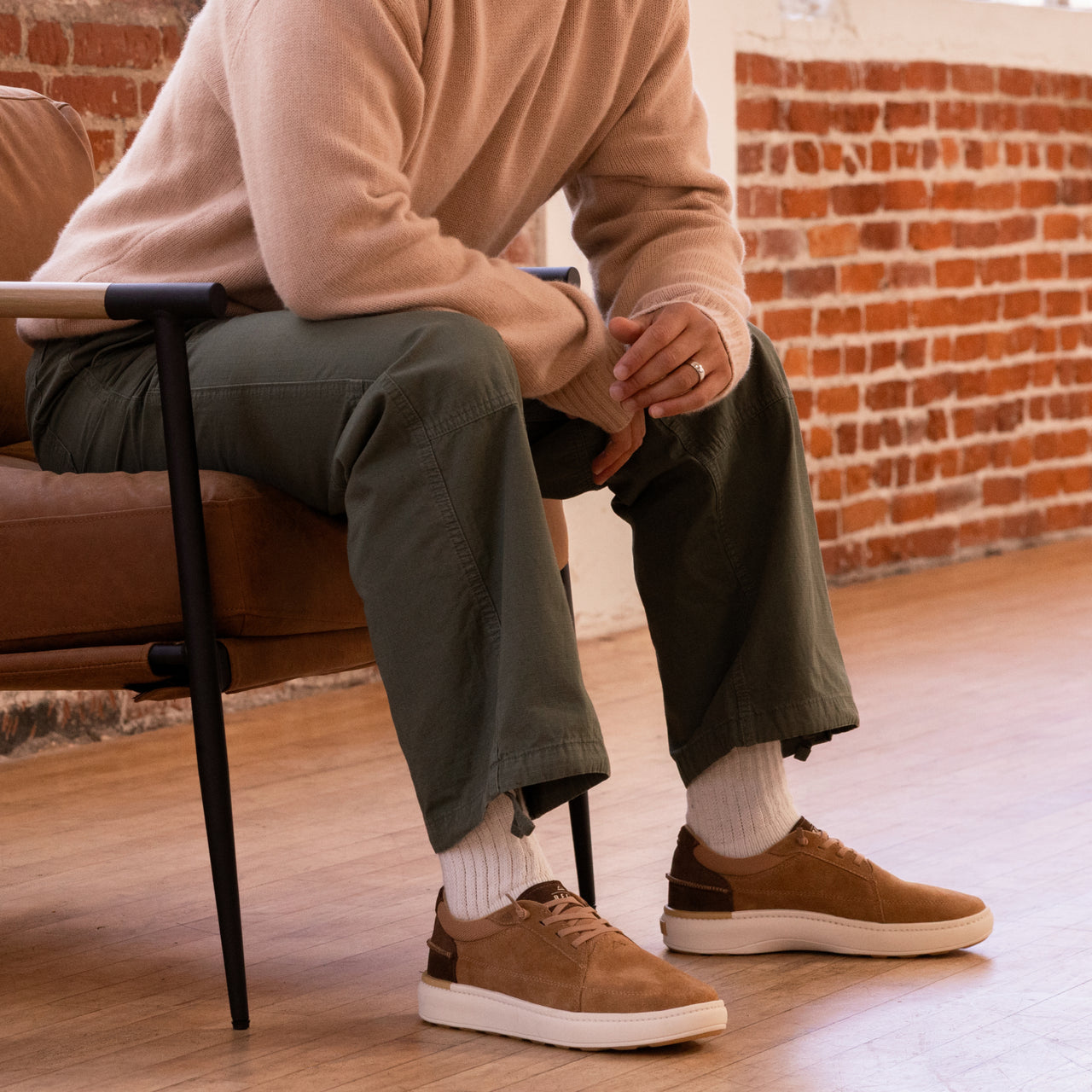 Man seated indoors wearing Verano shoes facing right, showcasing lightweight suede design with cushioned sole and arch support