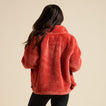 Woman wearing a red Pilot Sherpa Jacket from the back, showcasing its soft, comfortable, surf-inspired apparel design.