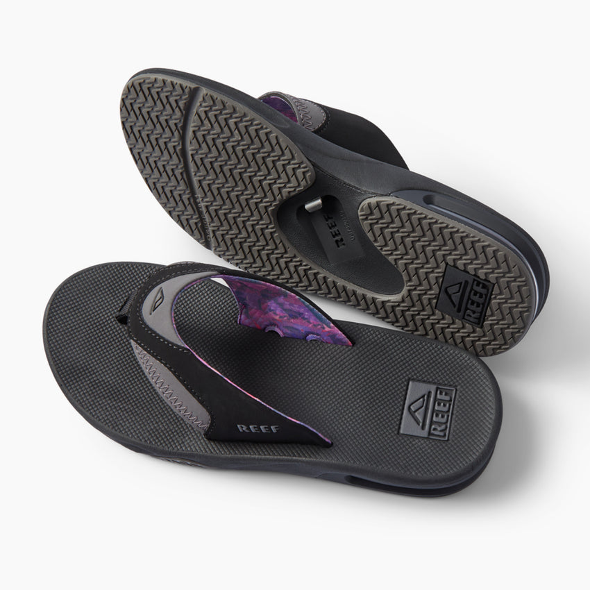 Fanning REEF black flip flops, one facing left with outsole visible and one facing right with footbed visible