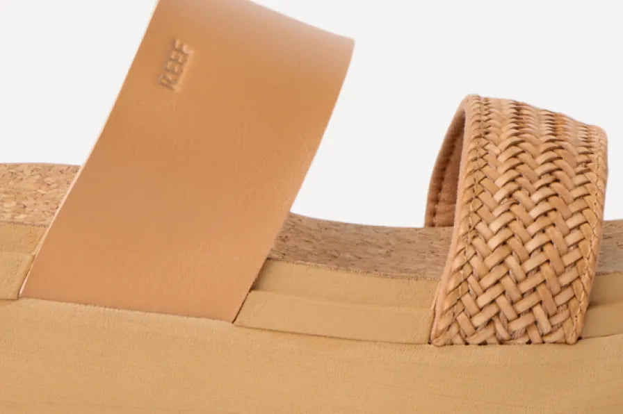 Close-up side view of tan platform slide sandal with smooth and woven straps, highlighting cushioned cork footbed comfort.