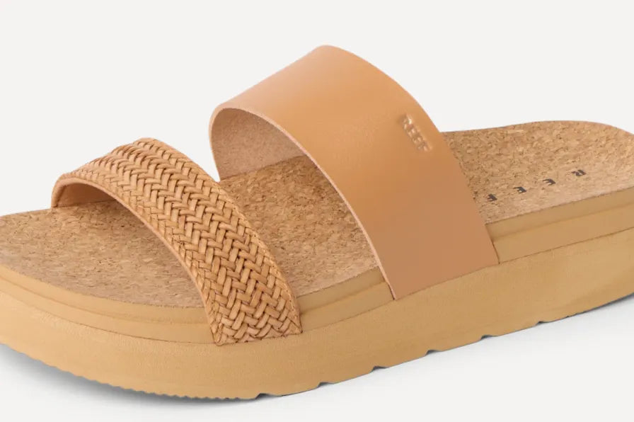 Side view of tan slide sandal facing right with braided front strap and smooth upper strap on cushioned footbed
