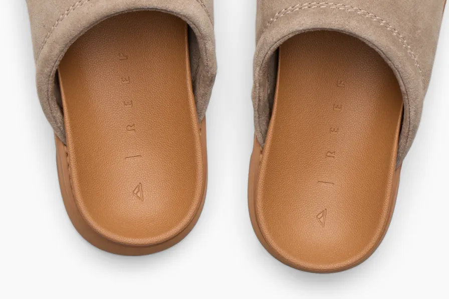 Top view of tan slip-on sandals with soft cushioned footbeds embossed with subtle REEF logo for beach comfort
