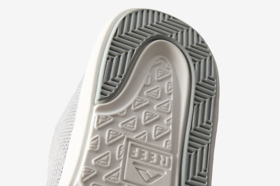 Close-up of the outsole facing upward showing textured tread with REEF logo and durable, water-friendly materials.