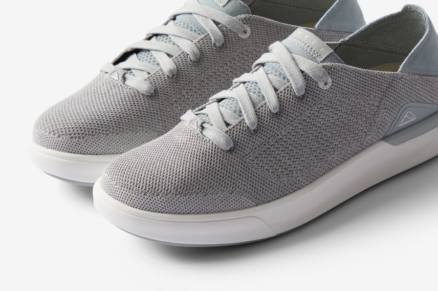Close-up of light gray sneakers facing forward with breathable knit uppers and cushioned midsoles for all-day comfort