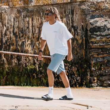 Phantom Slab black slides facing left on a beachside walk with cushioned comfort and arch support
