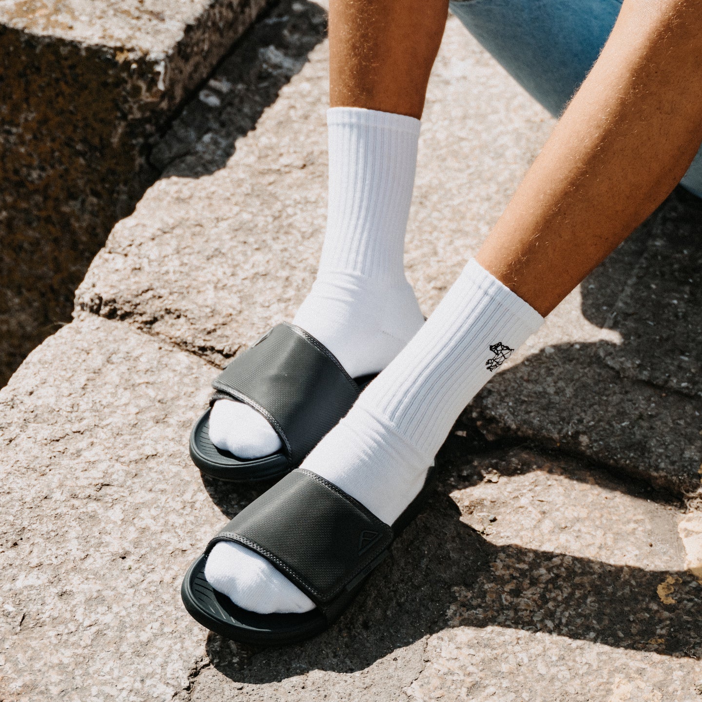 Phantom Slab black slides facing left on a person wearing white socks with cushioned comfort