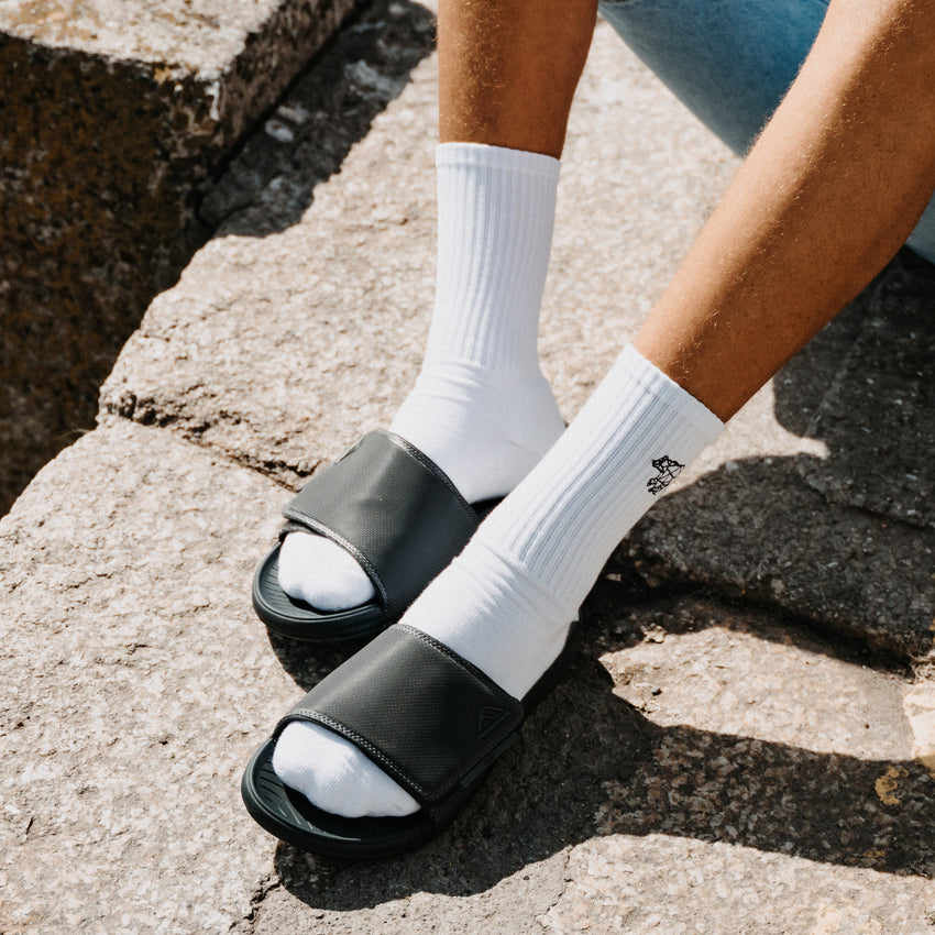 Phantom Slab black slides facing left on a person wearing white socks with cushioned comfort