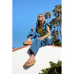 Woman sitting outdoors wearing tan Cushion Vista Hi sandals facing left with arch support and soft cushioning visible