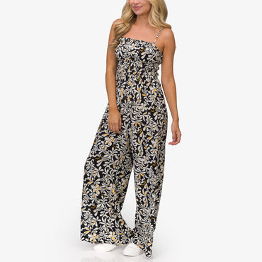 Woman wearing a black floral Sandy Romper standing front view with white shoes, beach-inspired comfort apparel for everyday wear.