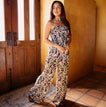 Woman wearing a black floral Sandy Romper standing indoors by a wooden door, showcasing beach-inspired comfortable apparel.