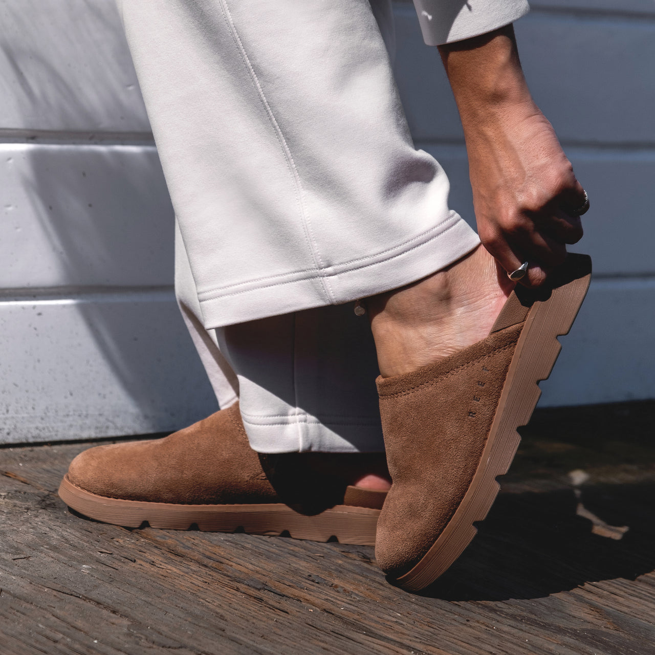 Close-up of left foot wearing brown suede Vista Luxe Mariana clog facing right, showing slip-on design and textured sole.