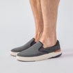 Del Mar Slip On facing right on model's feet, men's black slip-on sneaker with breathable knit upper and cushioned sole for comfort.