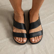 Feet wearing black Cali Solana sandals facing forward on neutral fabric, highlighting cushioned, water-friendly platform sandals.
