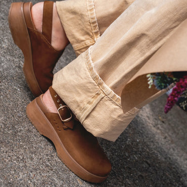 Vista Skye Rosa brown clogs facing left, showing side profile with adjustable backstrap and platform sole in casual outdoor setting.