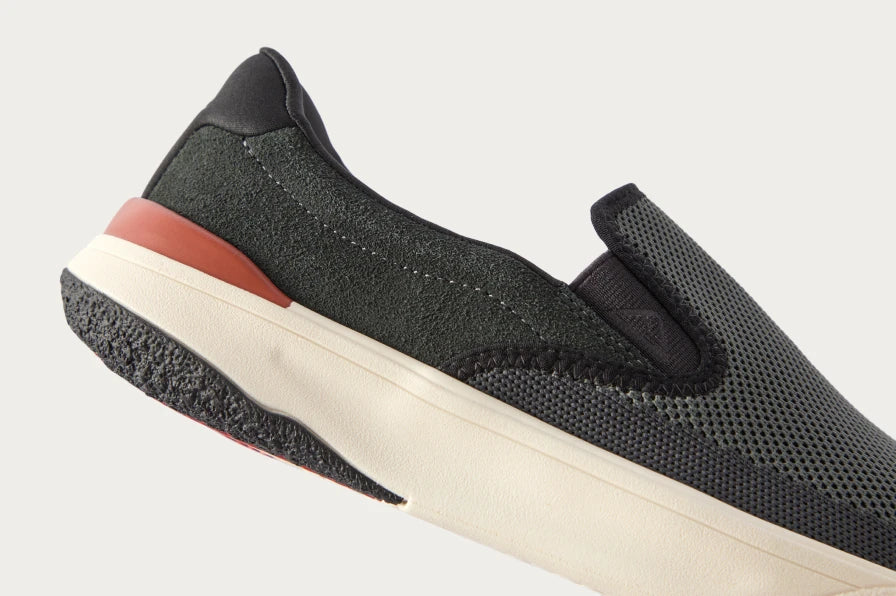 Side view of black slip-on sneaker facing right with breathable mesh upper and cushioned sole for comfort.